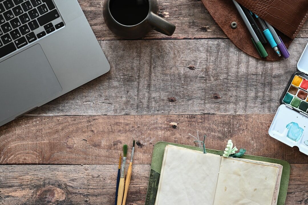 Laptop and open notebook on a wooden desk workspace