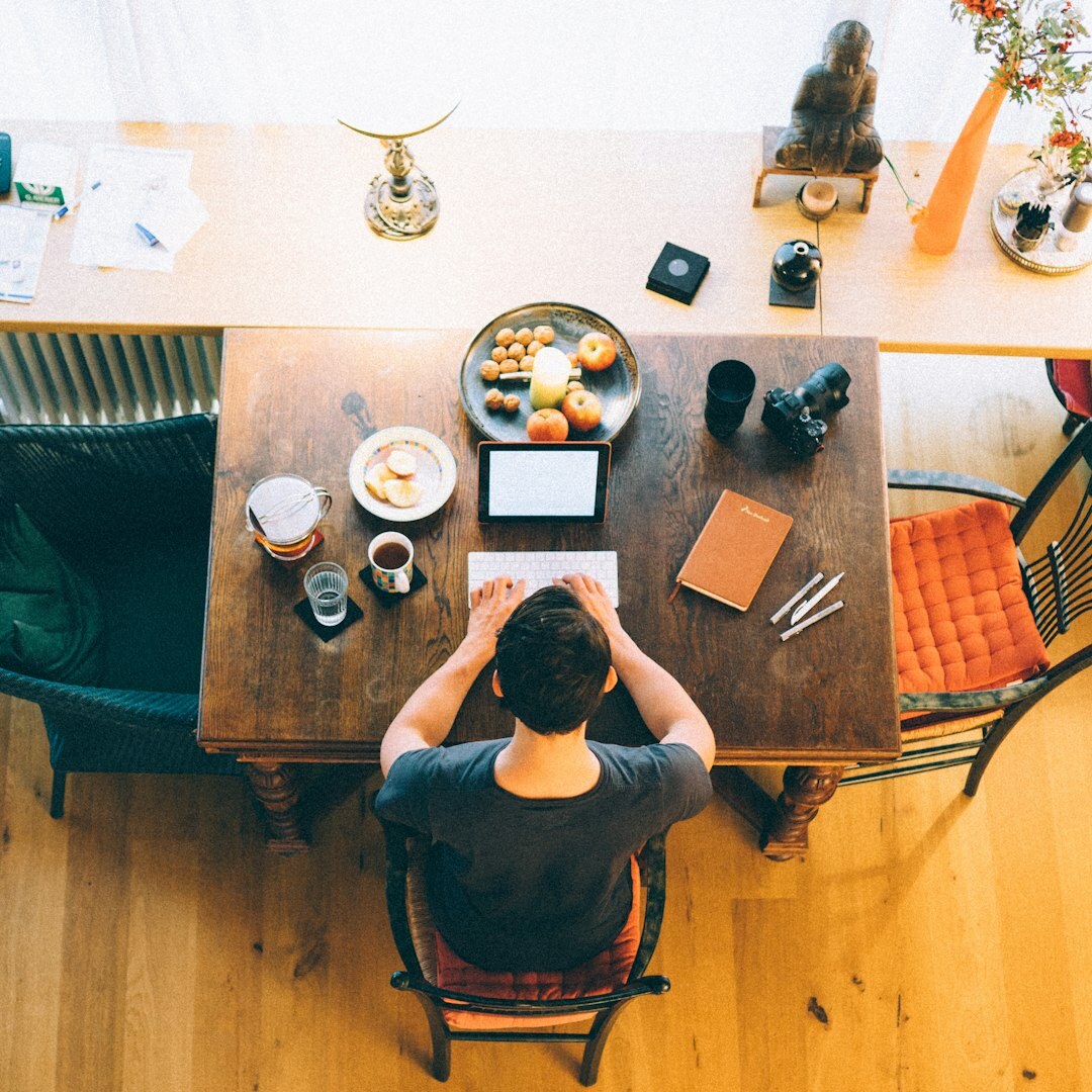 Woman writing thoughtfully in a journal at a sunlit desk