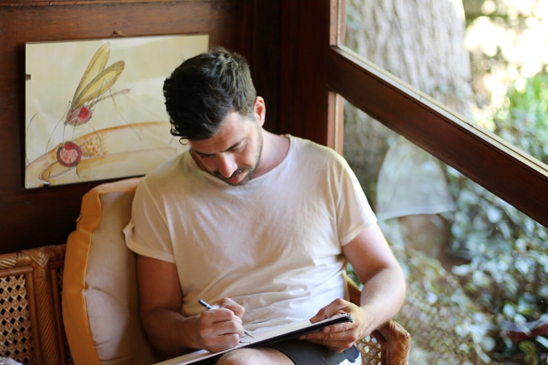 Person writing in a journal near a bright window